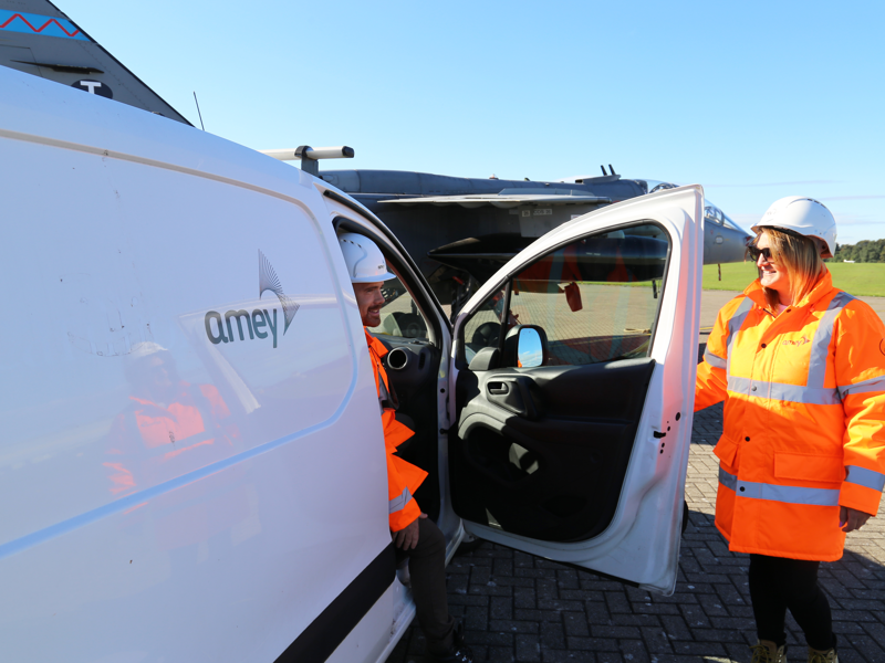 Image of a man sat in a van, with the door open, talking to a woman