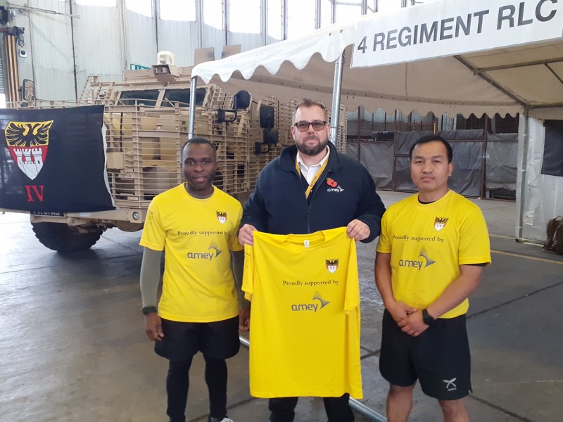 Image of Amey employee holding a yellow T-Shirt, stood with two men in yellow T-Shirts.