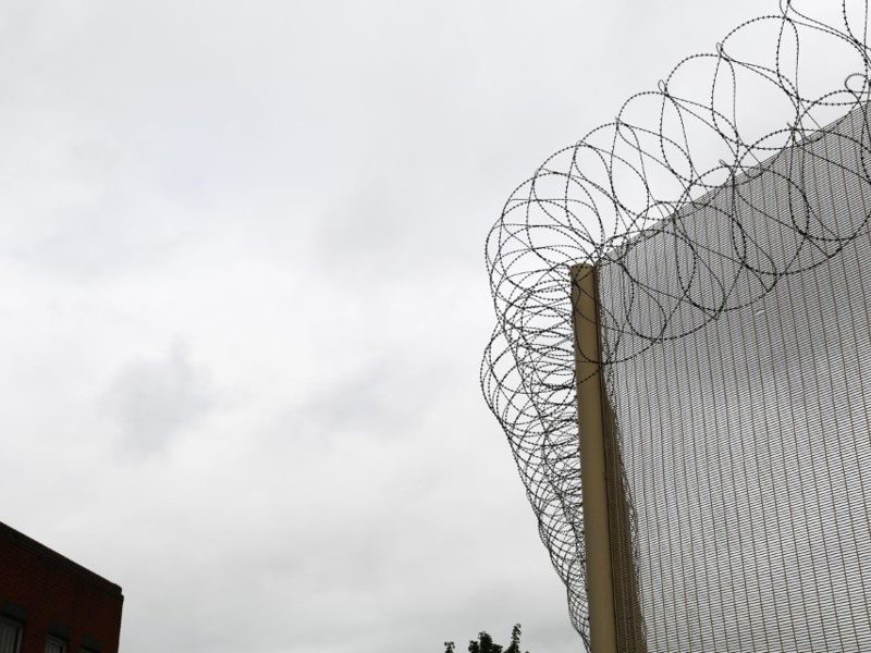 Image of a highly secured fence, topped with barred wire.
