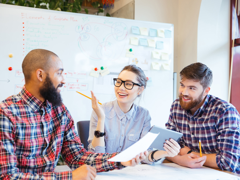 three people working at a desk.