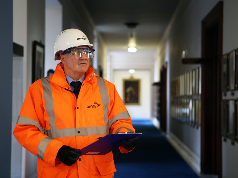 Image of an Amey employees in PPE, stood in a corridor. 