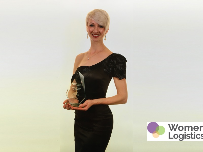 An image of a women in formal attire, holding an award.