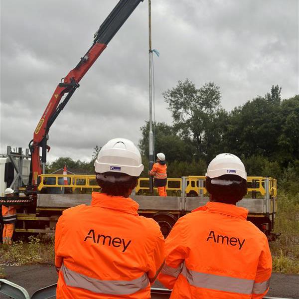 Two people in PPE, stood in front of a crane.