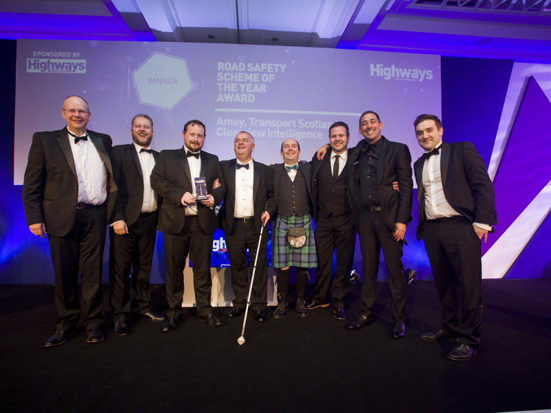 A group of Amey employees, in formal attire, holding an award.
