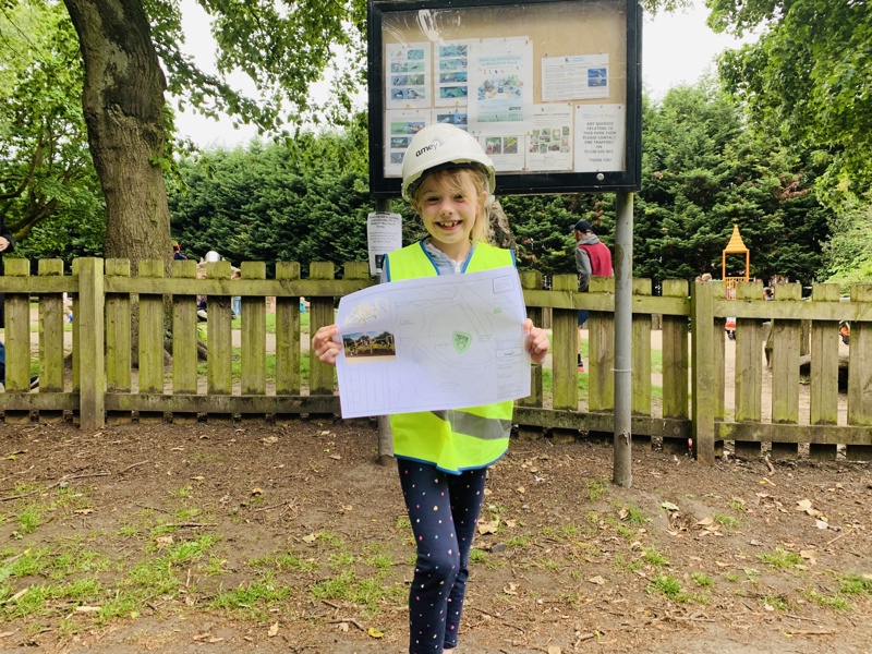 Image of a child in PPE, holding a drawing. 