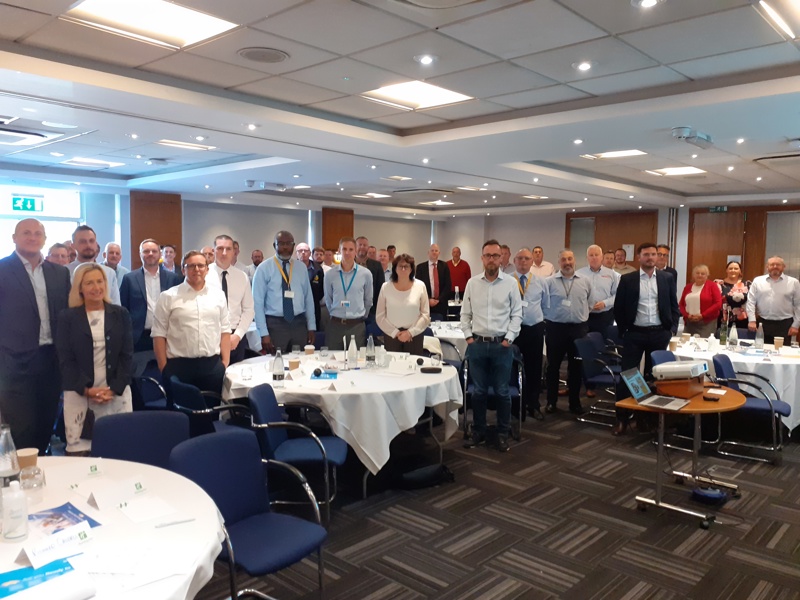 Image of a conference, with people standing round tables.