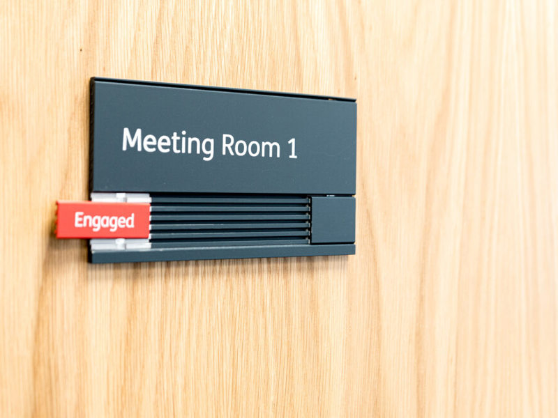 Image of a meeting room, with an 'engaged' sign on the door.