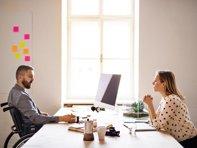 two people sat opposite each other at a desk.