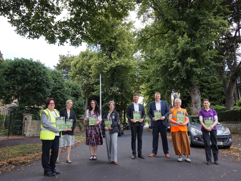 Amey employees standing on a road, holding a brochures. 