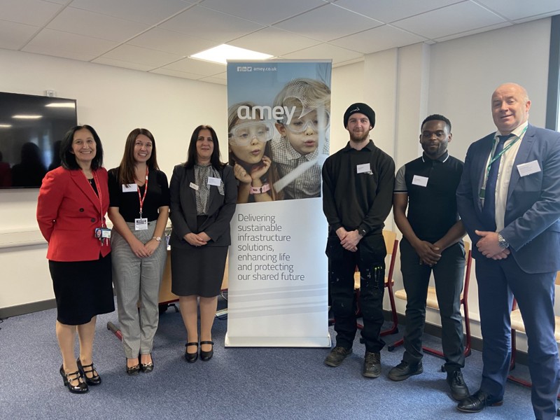 Image of 6 Amey employees, three stood either side of an Amey banner stand.