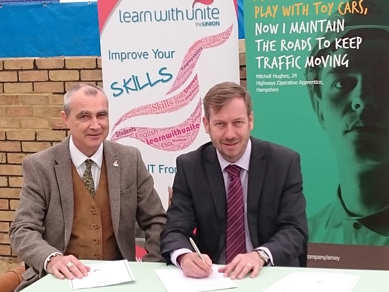 Image of two men at a table holding a pen and paper.