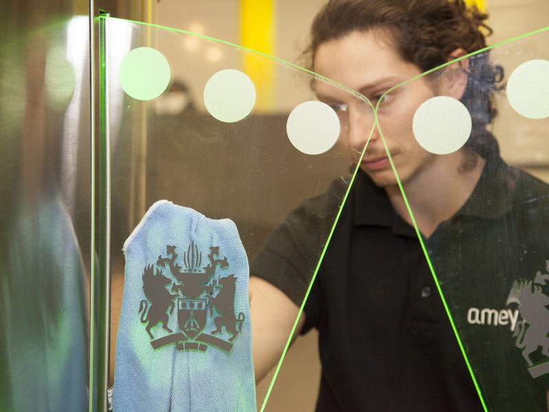A male Amey cleaner, cleaning a window.