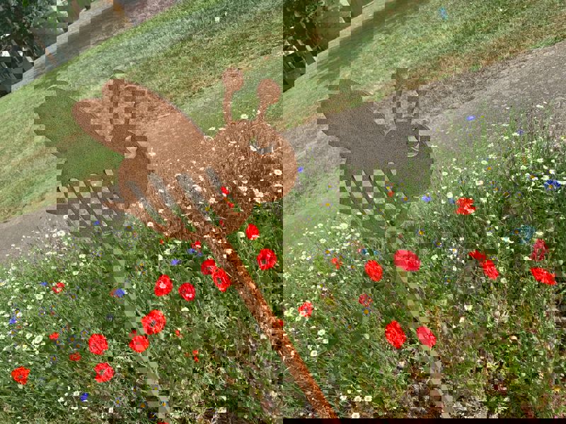 Wooden bee steak in front of wild flowers.