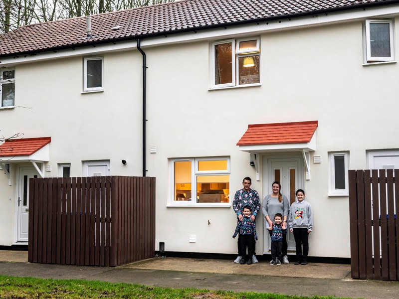Image of a service family stood in front of their new home.