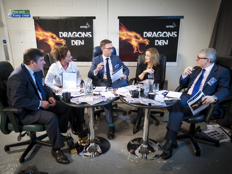 A group of people sat round two tables covered in paperwork.