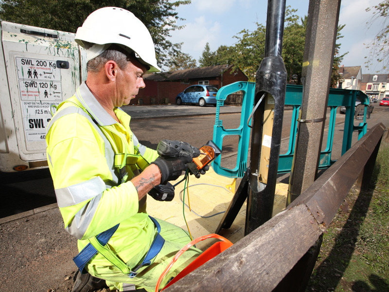 A man in PPE, carrying out a streetlight repair.