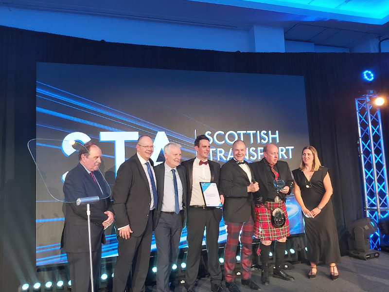 A group of Amey employees, in formal attire, holding an award.