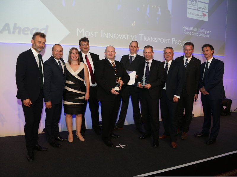 A group of Amey employees, in formal attire, holding an award.