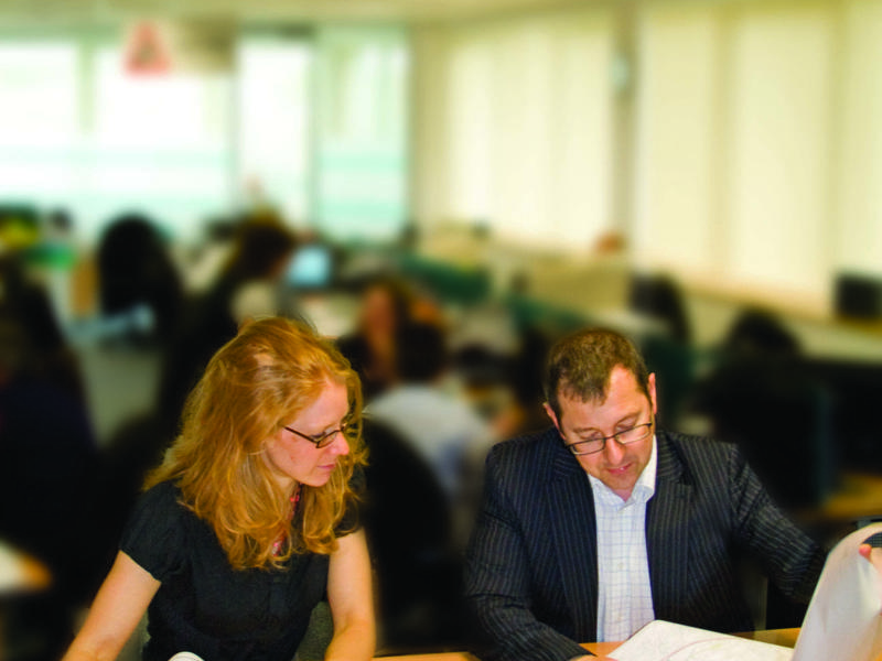 A man and a woman sat at a desk, inspecting a map.