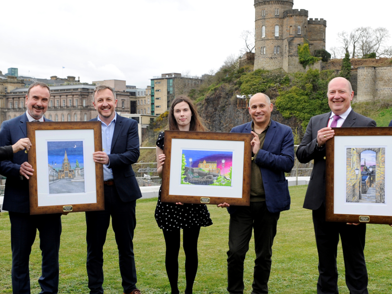 A group of Amey employees, holding three pictures in frames.