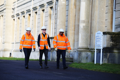 Image of three Amey employees walking in front on a building.