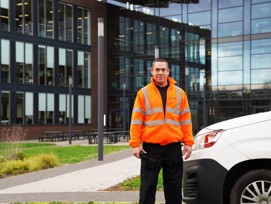 Amey employee standing next to a van, in front of a building.