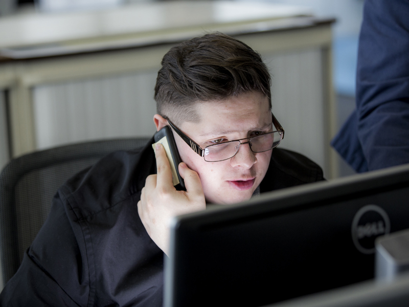 Image of a man at his desk talking on a mobile phone.