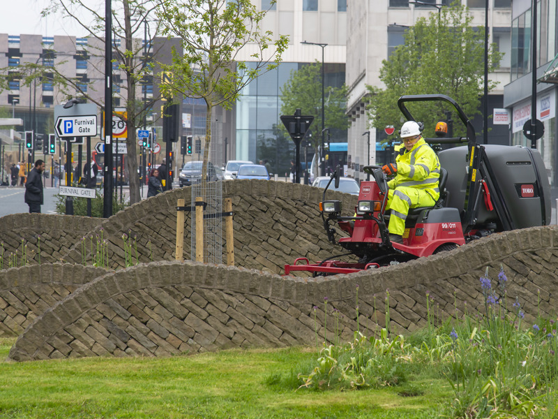 A man in PPE on a street cleaning vehicle.
