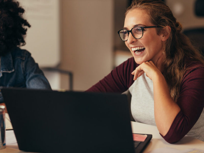 women smiling in front of a laptop