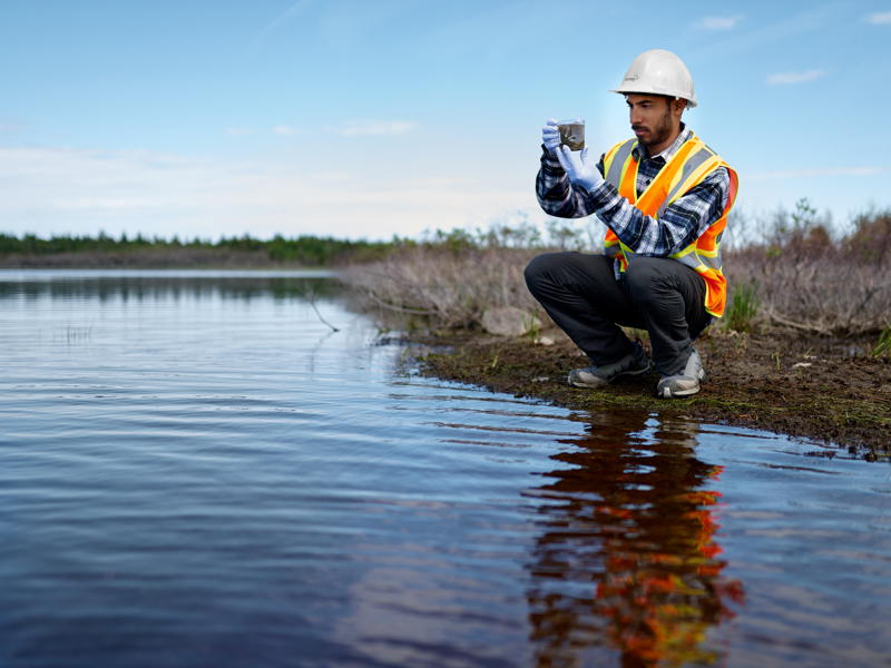Image of a man taking a photo of a lake.