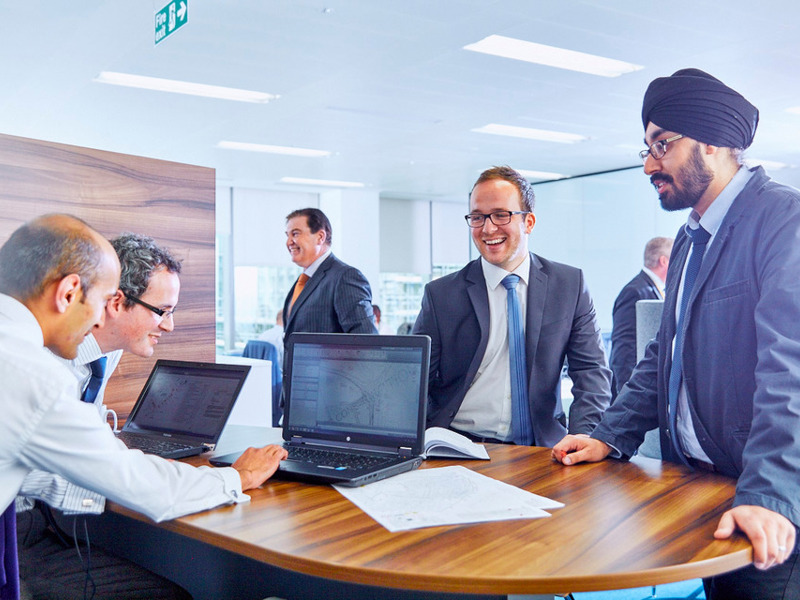 a group of men stood chatting round a desk.