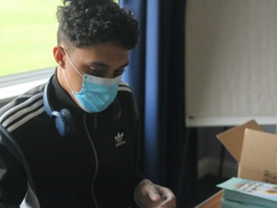 Image of a young man sat in an cabin wearing PPE