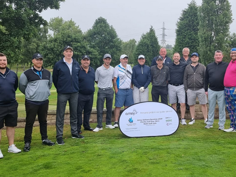 Image of people stood in a row, at a golf course at a charity golf day. 