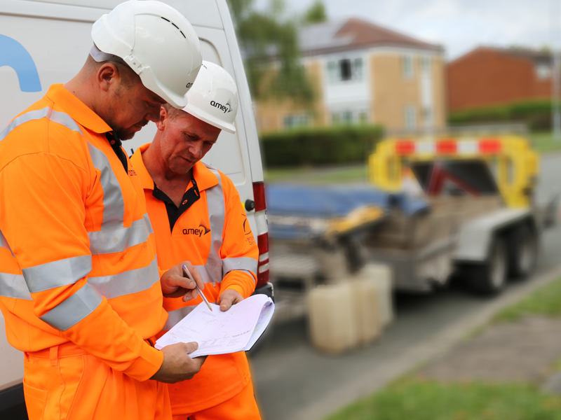 Image of two Amey employees inspecting a document,
