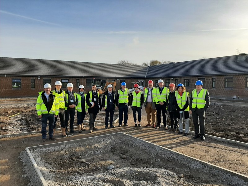 Image of Amey employees line up in a v shape stood in front of a square hole.