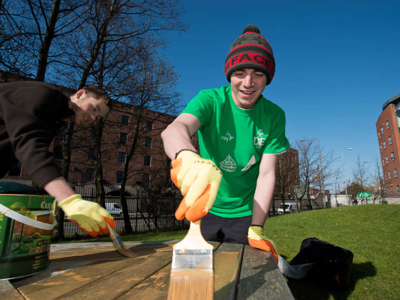 Two men painting a park table.