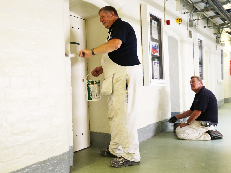 two men painting a hallway.