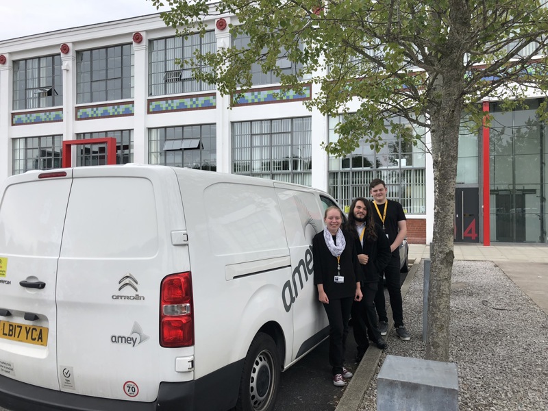 Three people stood next to a Amey van.