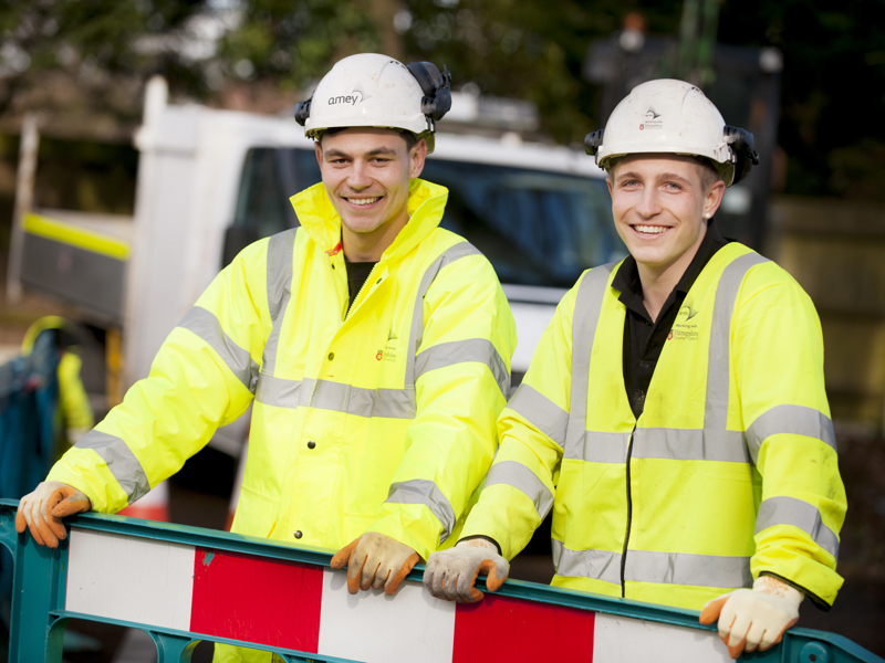 two men in PPE stood at a temporary fence.