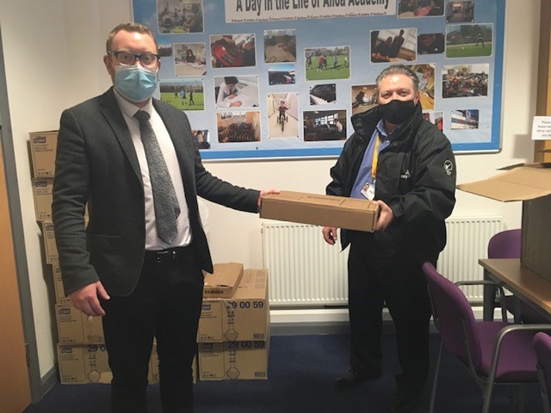 man handing a laptop to a woman.