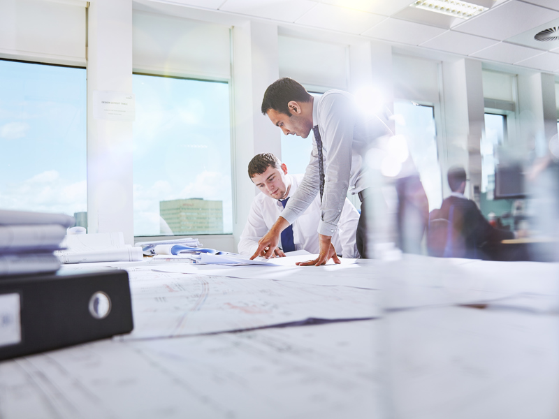 Two people inspecting documents at a desk.