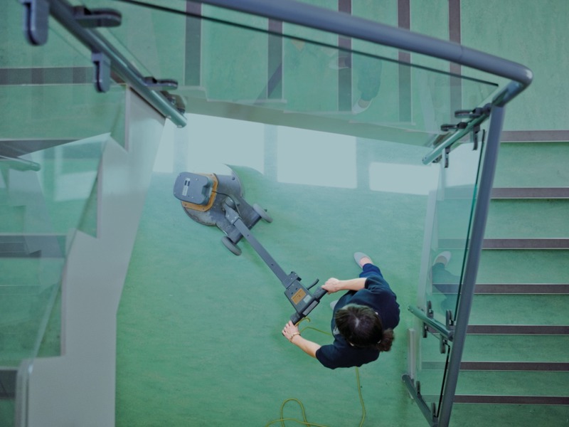 ariel image of a person cleaning the floor at the bottom of a stairway.