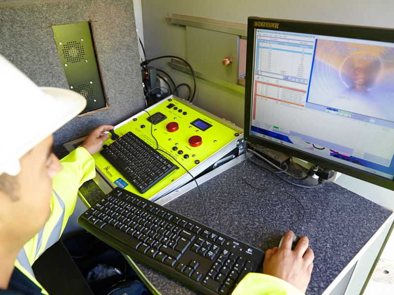 A man in PPE, sat at a computer. 