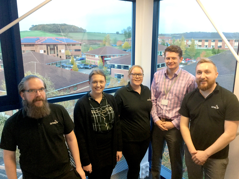 A group of Amey employees, stood in front of a window.