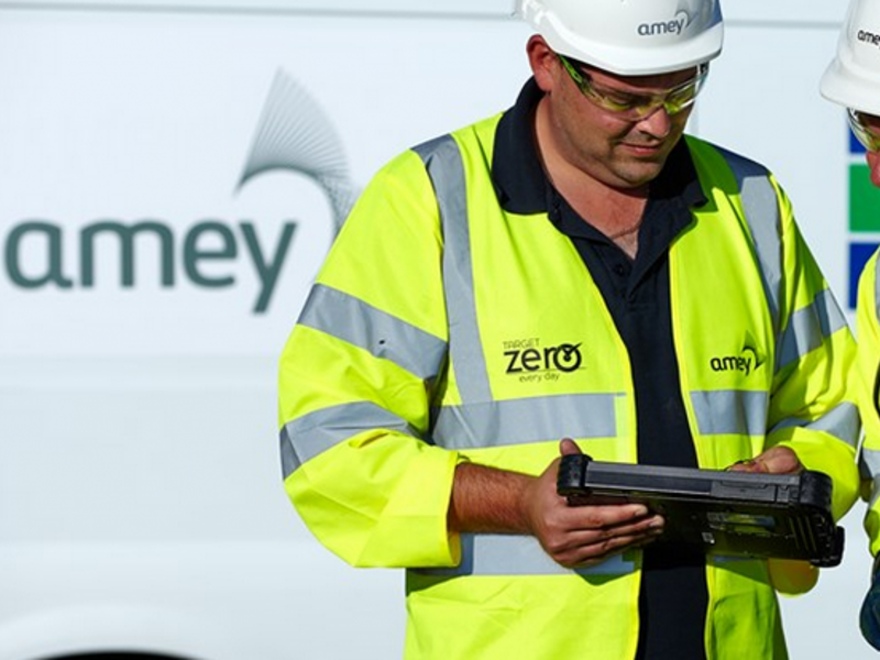 A man in PPE, inspecting a meter stood in front of a van.