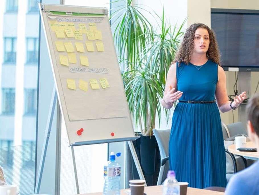 Image of a women giving a presentation to an audience 