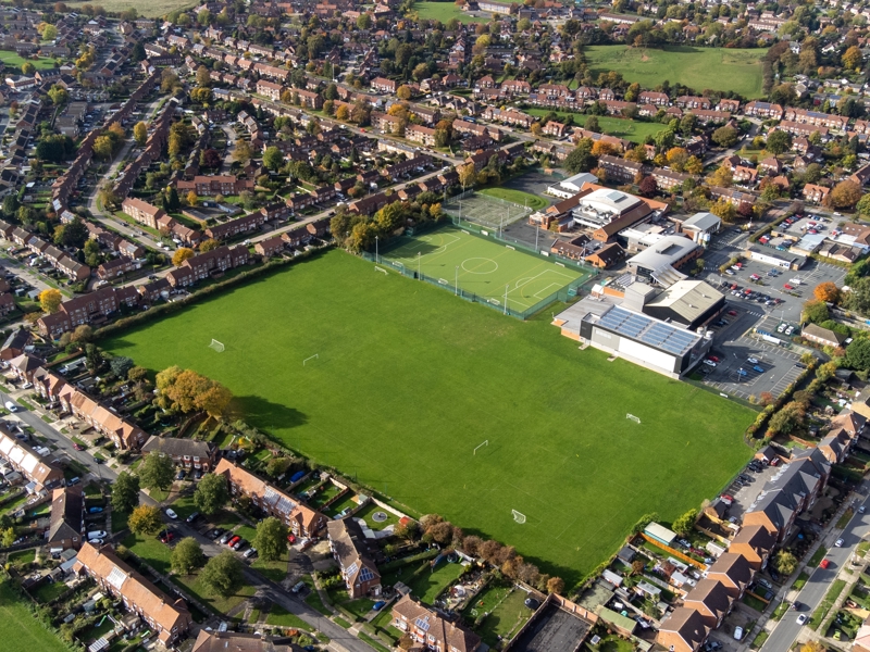 Aerial view of a secondary school campus with sports fields and surrounding residential housing.